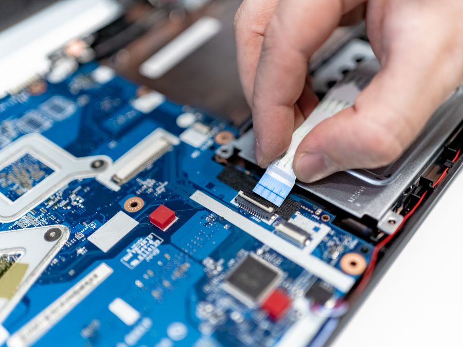 Técnico reparando la placa y conectores de una laptop HP en el taller de Cancún